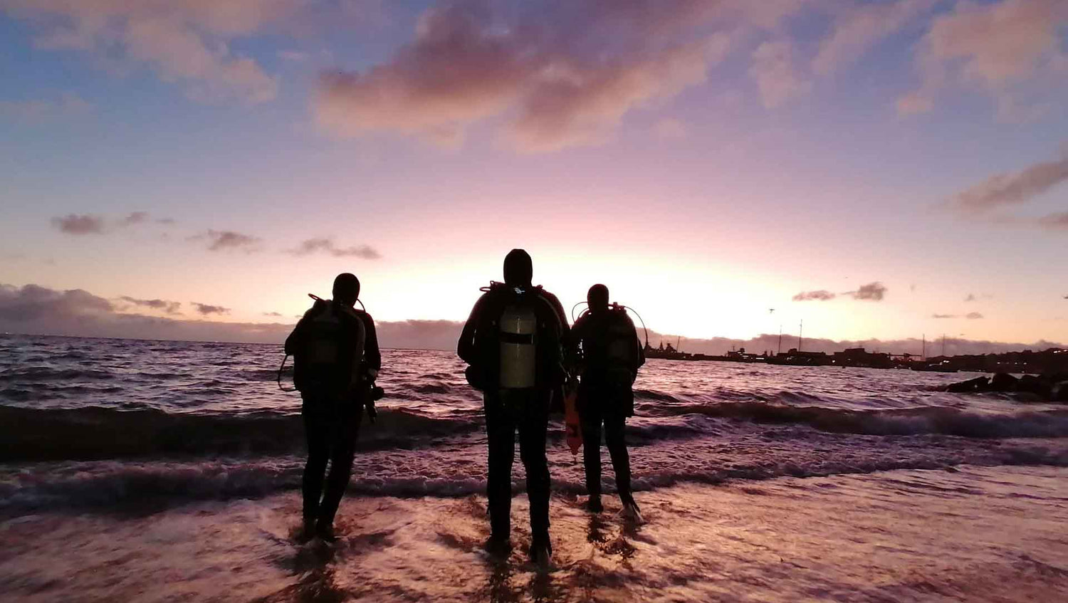 Divers entering the water at dawn at long beach in simonstown