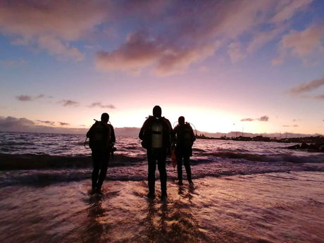 Divers entering the water at dawn at long beach in simonstown